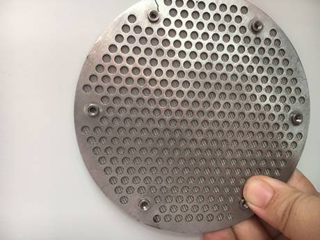 Eine Hand hält eine runde Form durchlöcherte Metall gesinterte Filterdiskette.